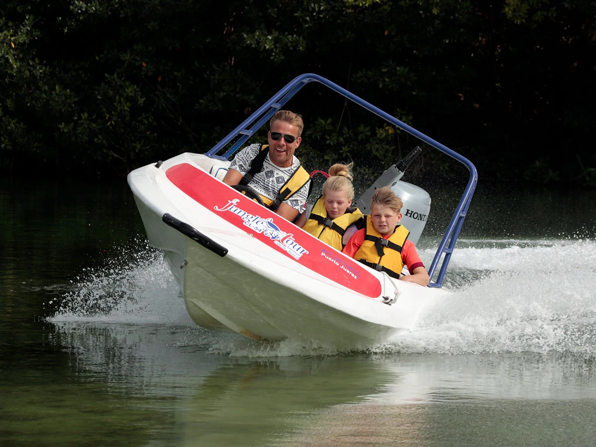 Dad and his two children are aboard a Jungle Tour Adventure speedboat, sailing at full speed through the canals of the lagoon in Cancun and watch video button