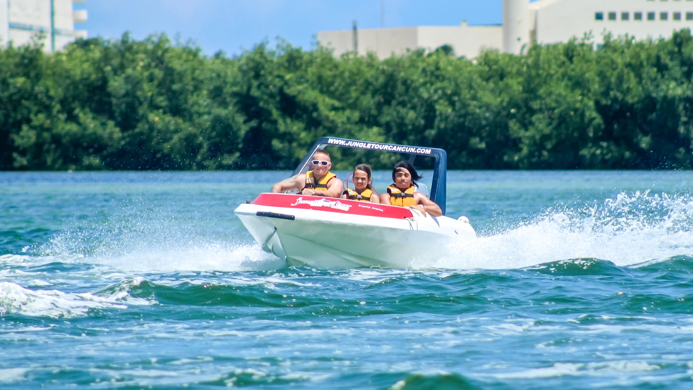 A family of 3 aboard a speedboat in Cancun speeding through the mangrove channels and watch video button